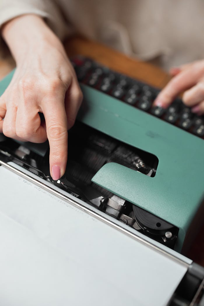 Hands typing on a green vintage typewriter, focusing on the mechanical keys and action.